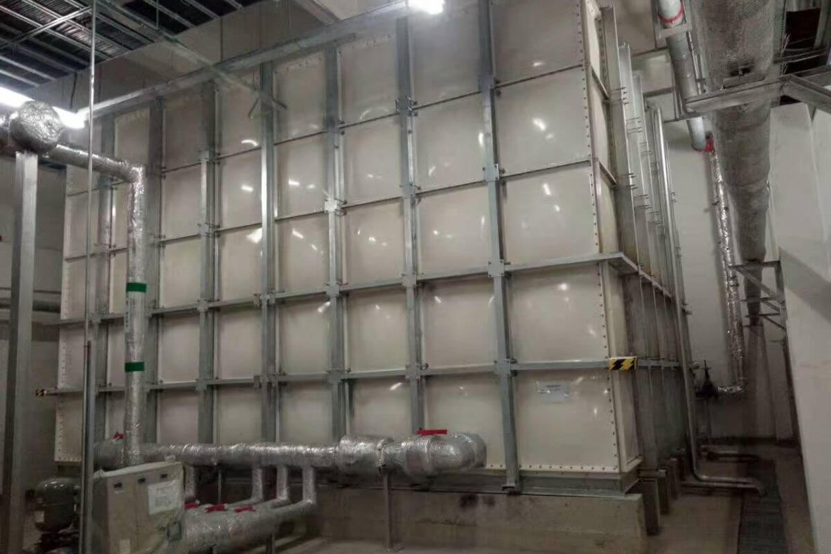 Large modular water storage tank installed indoors with connected insulated piping in a mechanical room