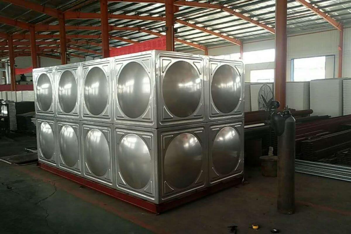Stainless steel modular water storage tank installed inside an industrial facility or workshop