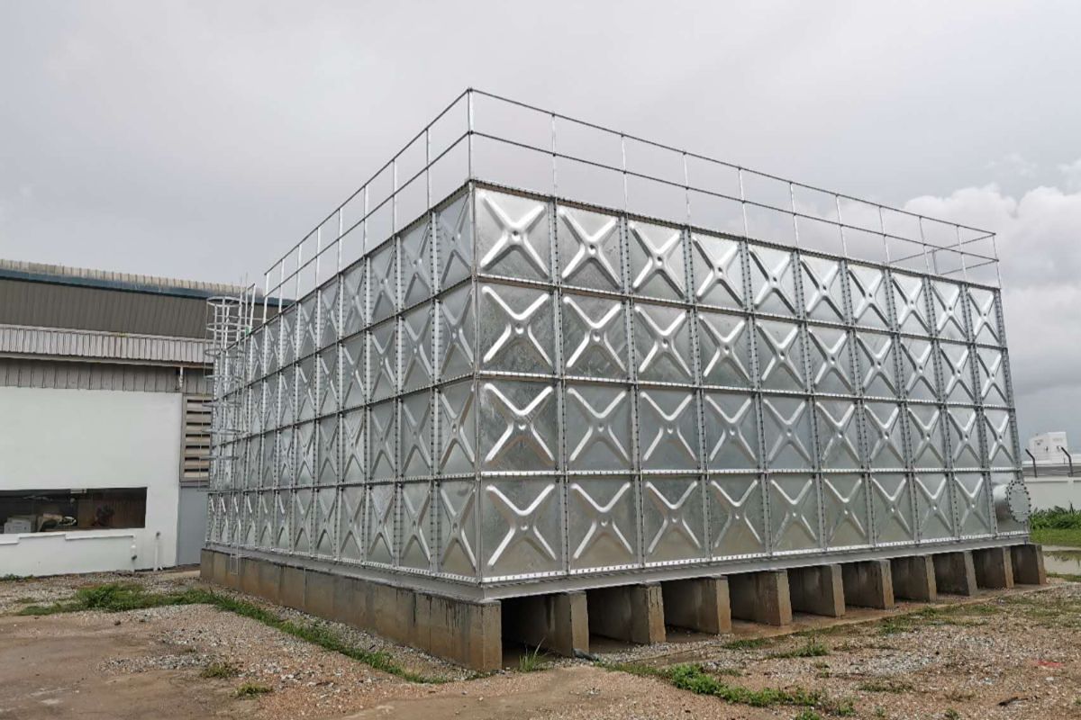 Galvanized pressed steel modular water storage tank equipped with safety guardrails at an industrial site.